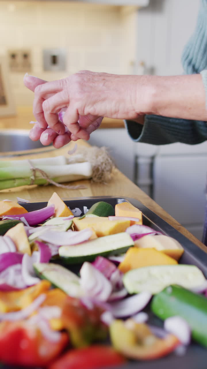 video vertical de una mujer caucásica mayor de pie en la cocina y preparando la cena