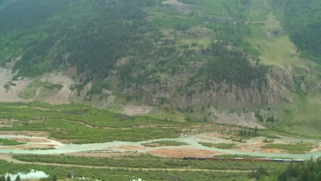 A-very-distant-shot-of-a-steam-train-passing-through-the-Rocky-Mountains