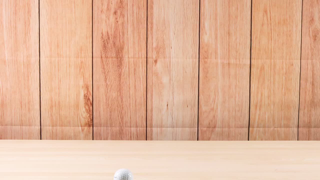 una pelota de golf rodando a través de un piso de madera