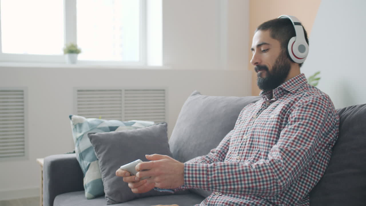 Uomo che ascolta musica e usa il telefono sul divano