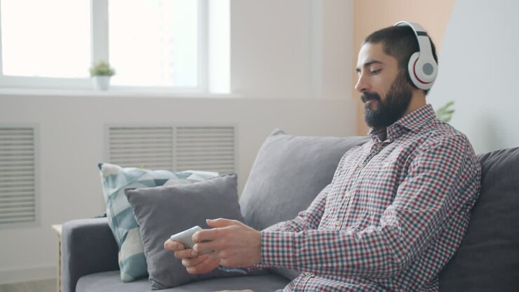 Uomo che ascolta musica e usa il telefono sul divano