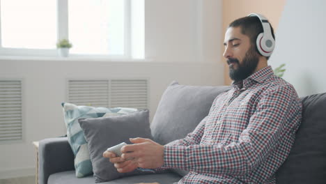 Man Listening to Music and Using Phone on Couch