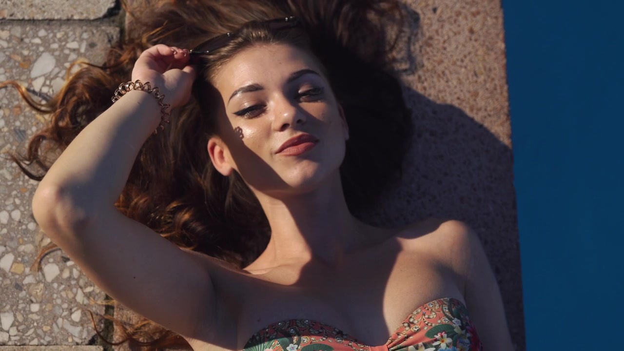 Giovane donna in relax a bordo piscina in estate