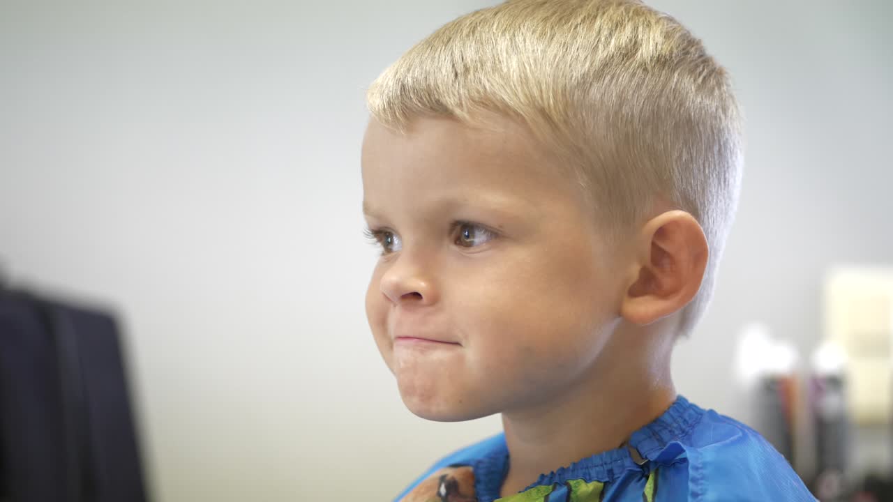 orgulloso chico divertido con un nuevo y lindo corte de pelo en la peluquería, mirando directamente a la cámara