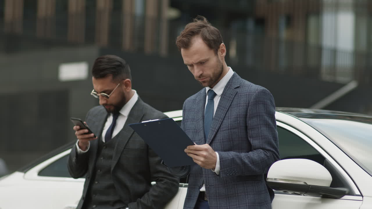 Two Businessmen Standing by Car