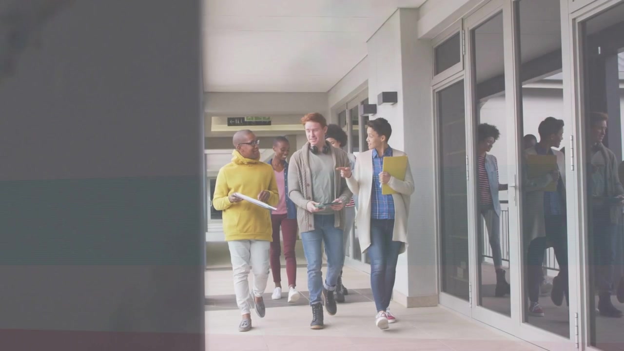 Studenti che si muovono tra le lezioni lungo il corridoio, passando un pilastro e una ringhiera, tenendo quaderni