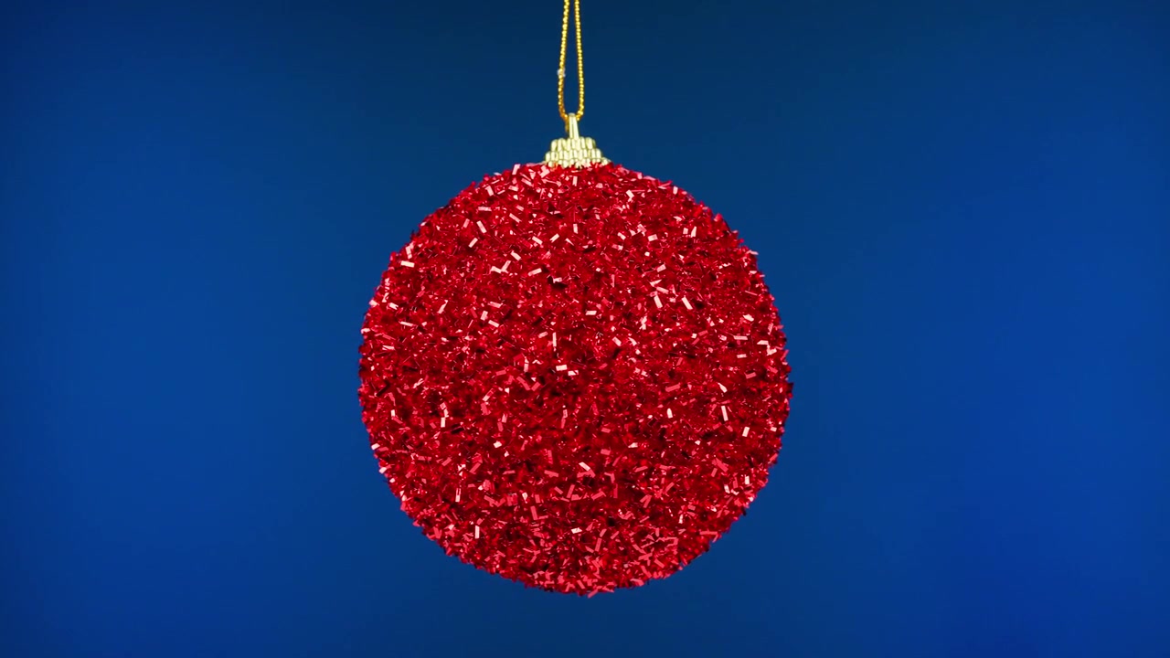 Roter Glitzer-Weihnachtsbaumschmuck hängt vor blauem Hintergrund