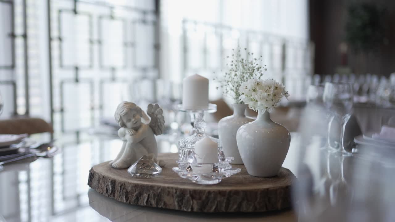 table centerpiece featuring a small angel statue, candles, and floral vases