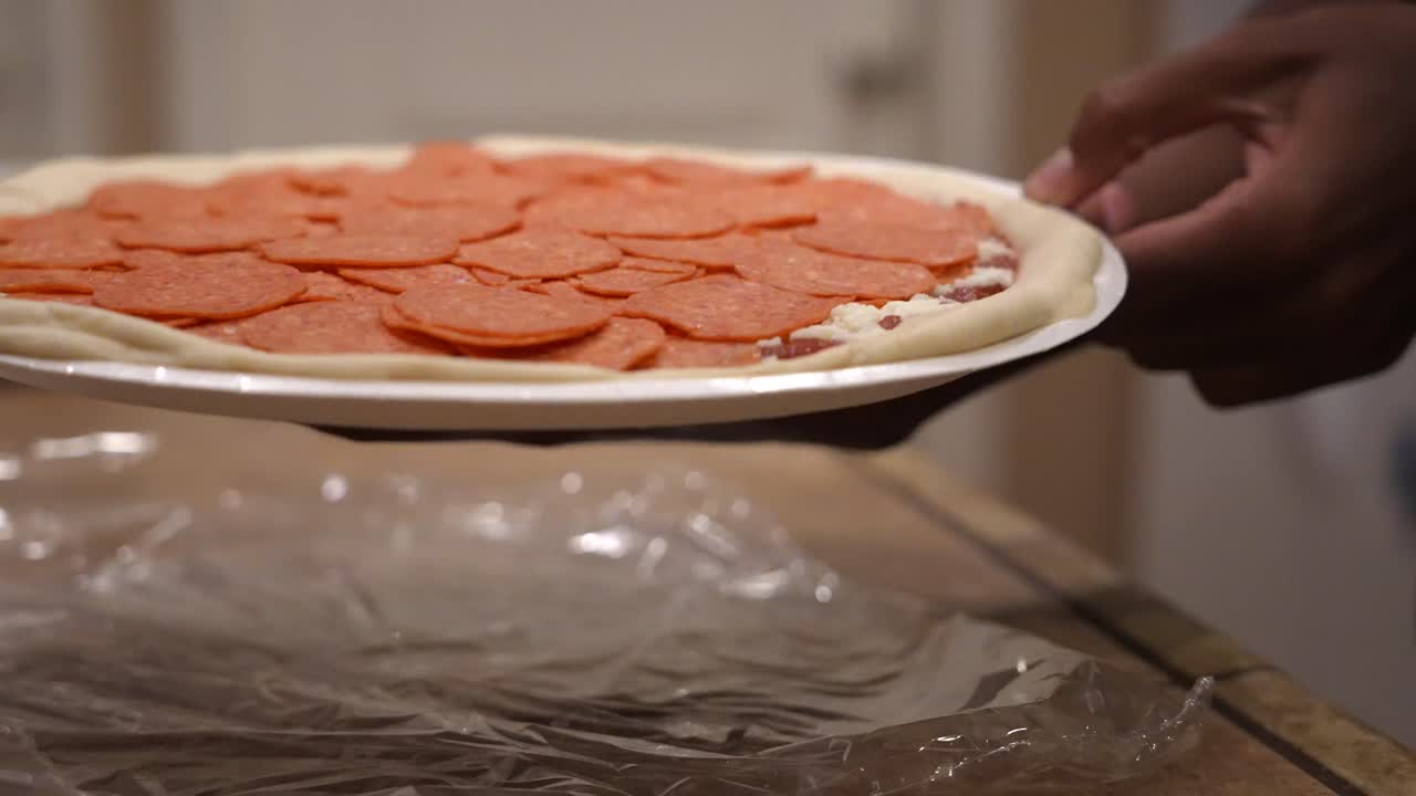 colocando una pizza de pepperoni cruda en el horno para hornear - cámara lenta