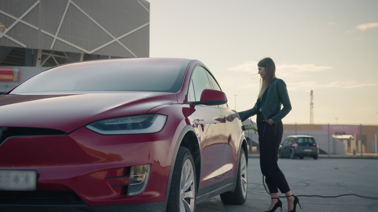 충전소 에서 전기 자동차 를 충전 하는 여자