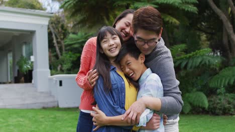 Smiling-asian-parents-hugging-happy-son-and-daughter-in-garden