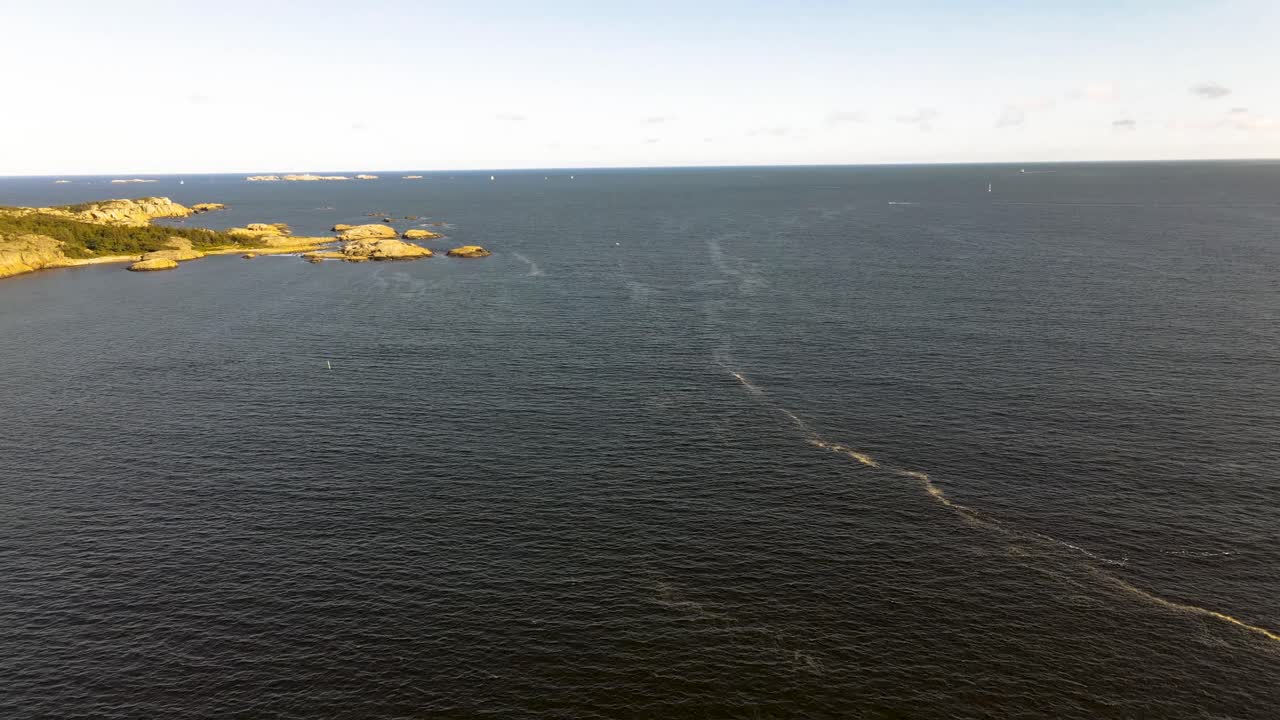 olas que crean espuma en la superficie del océano con veleros e islas en el fondo