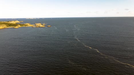 Wellen-Erzeugen-Schaum-Auf-Der-Meeresoberfläche-Mit-Segelbooten-Und-Inseln-Im-Hintergrund