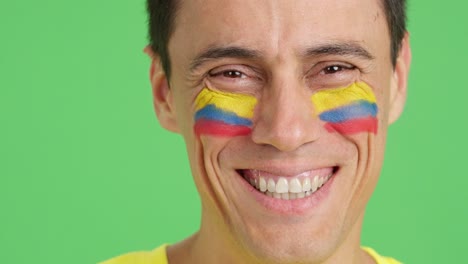 man with a colombian flag painted on the face smiling