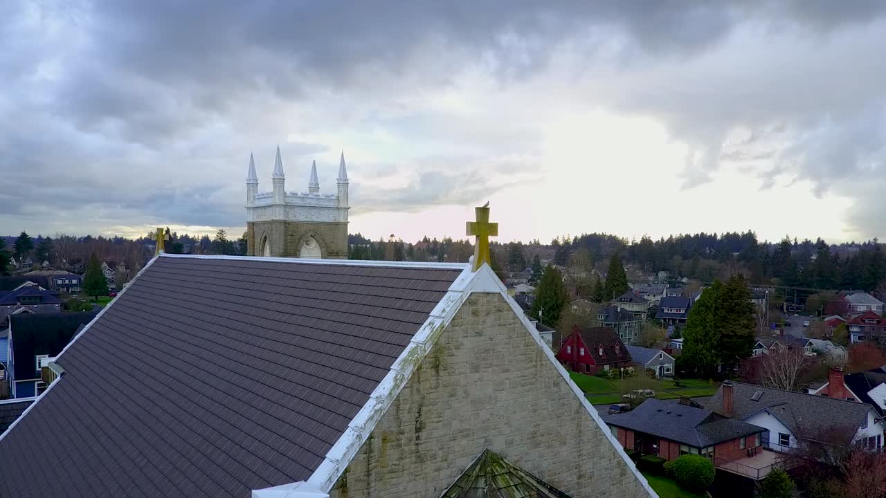 aerial shot slowly approaching a cross on the roof of Church of St Patrick, a stormy sky in the background