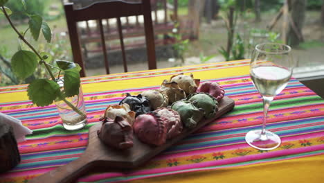 colorful table with a board of various flavored colorful empanadas and a glass of white wine