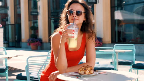 mujer disfrutando de una bebida y postre en un café al aire libre