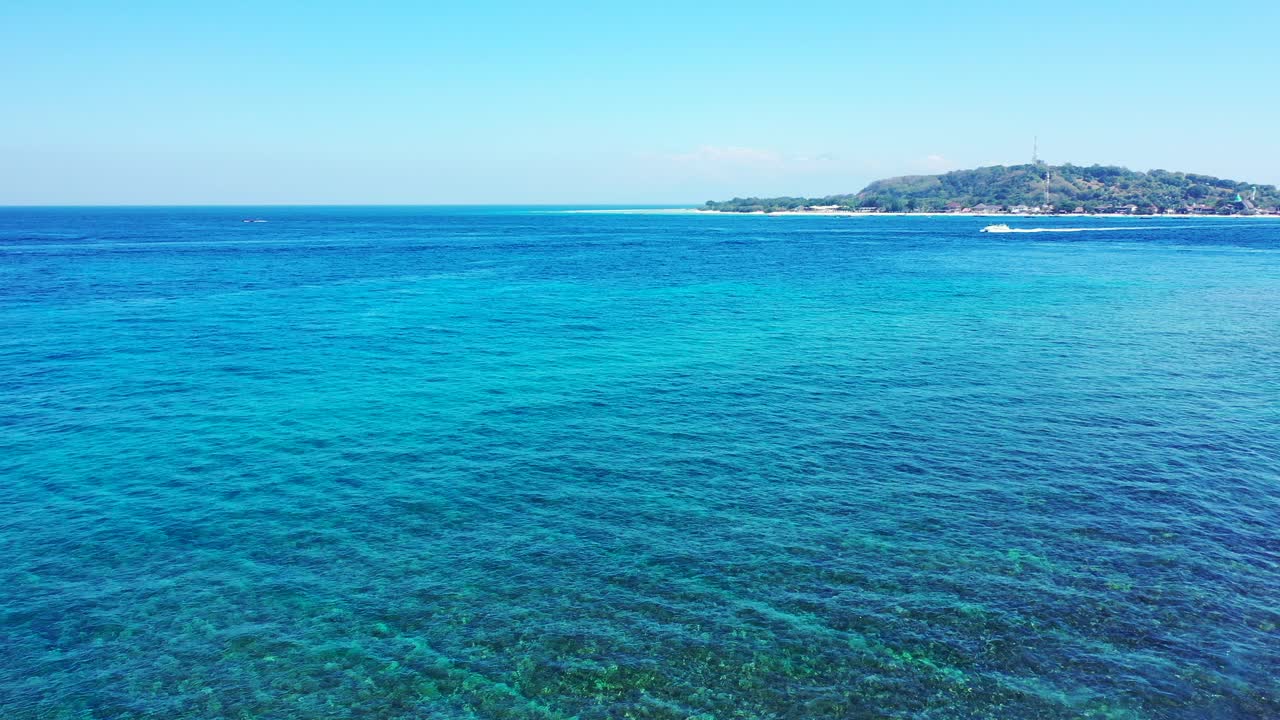 인도네시아의 해안선 위로 맑은 하늘이 있는 밝은 아침에 바다 바닥에 아름다운 자갈 무늬가 있는 아쿠아마린 얕은 석호 위로 날아갑니다.