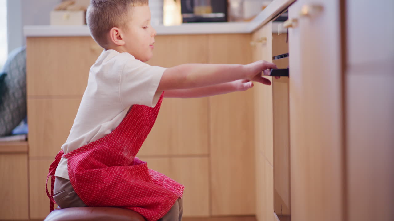 мальчик смотрит на торт, выпеченный в духовке.