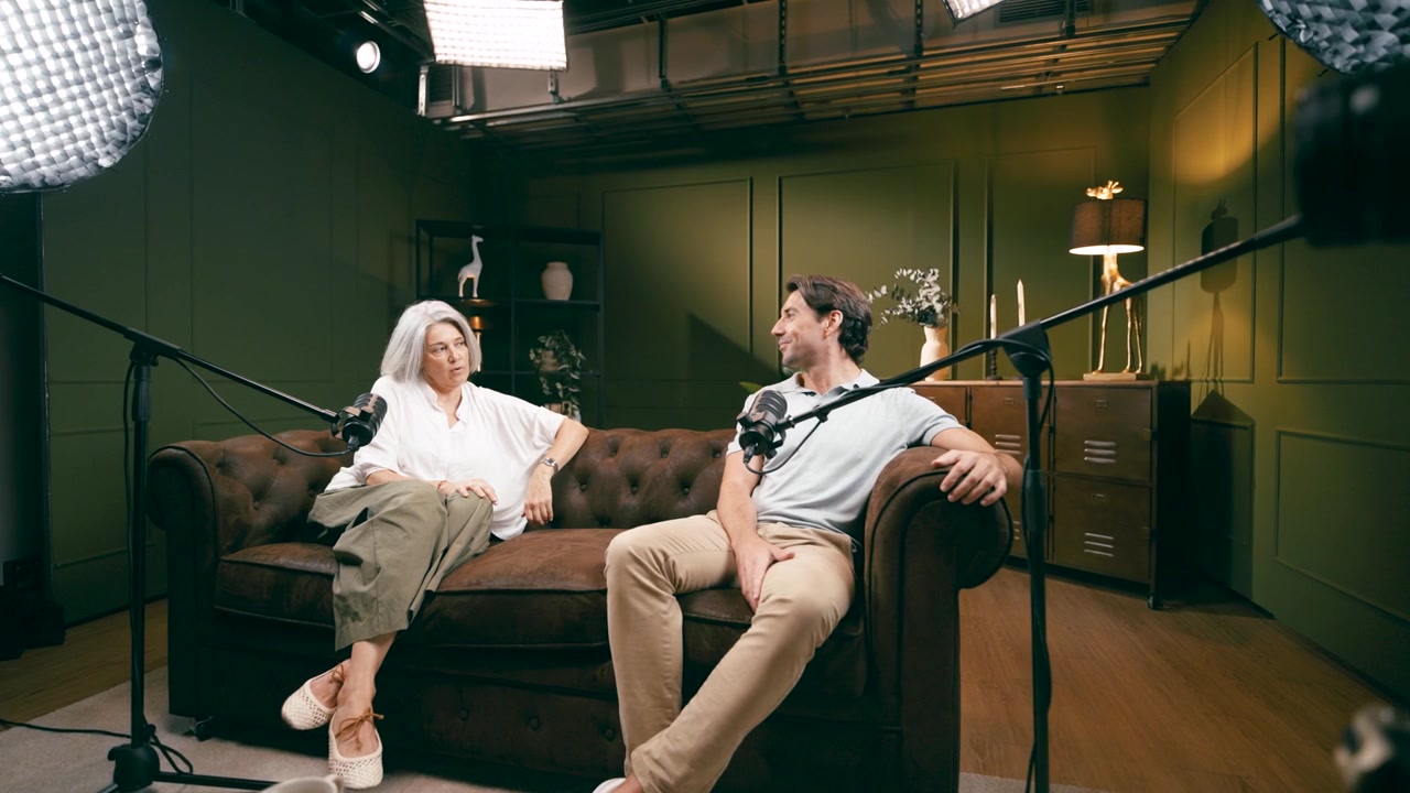 Deux personnes discutant sur un canapé dans un studio de podcast