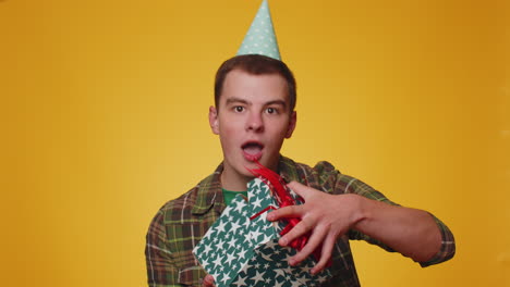 cheerful adult boy opening gift box and smiling joyfully, looking amazed satisfied with nice present