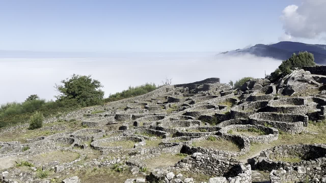 vista de cerca de las antiguas ruinas celtas en santa tecla, galicia, con una montaña cubierta de niebla en el fondo