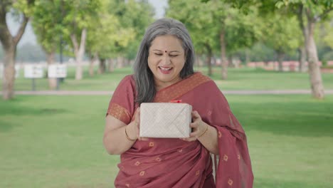 Happy-Indian-old-woman-receiving-a-gift-in-park