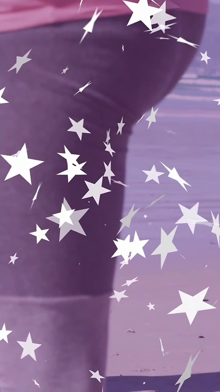 Video verticale: La telecamera si muove verso l'alto mentre una donna gira stelle fluttuanti con una tinta viola, mostrando un top rosa alla moda.