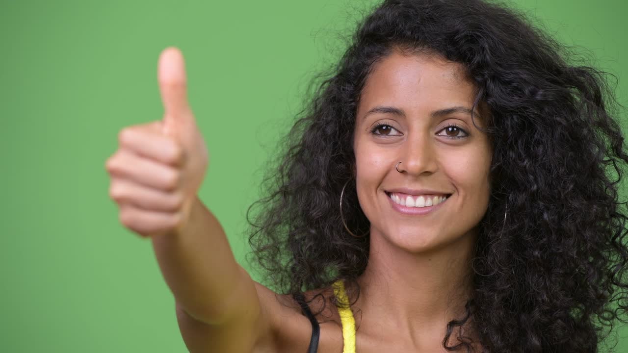 Young beautiful Hispanic woman giving thumbs up