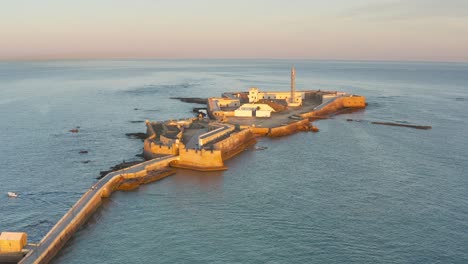 vista aérea de una histórica fortaleza costera y un faro al amanecer o al atardecer