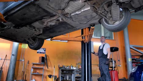 mechanic inspecting car on lift in auto shop
