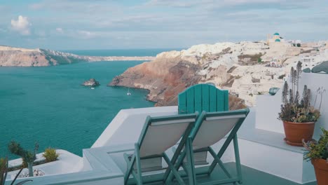 Two-lounge-chairs-in-front-of-Oia-village,-Santorini