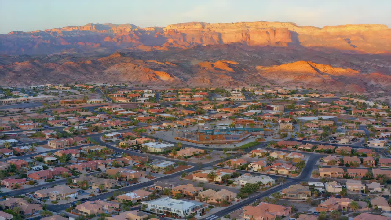 Vista aerea di una vasta comunità nel deserto adagiata contro maestose montagne al tramonto
