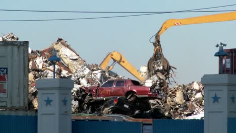 cranes lift and move scrap metal around abandoned and destroyed cars in a junkyard or scrap metal yard 2