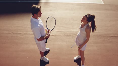 woman and man playing tennis on a sunny day