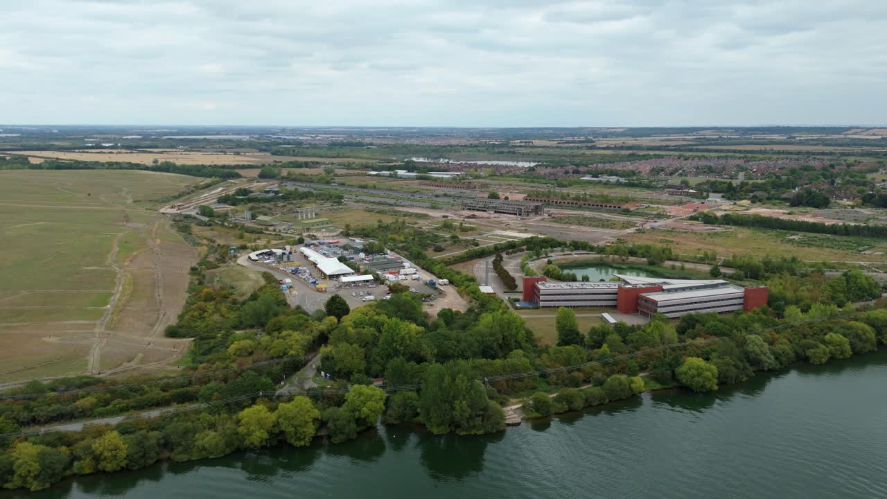 Drone aerial footage showing waste recycling centre and university campus in Bedford England UK highlighting large lake and urban overcast environment