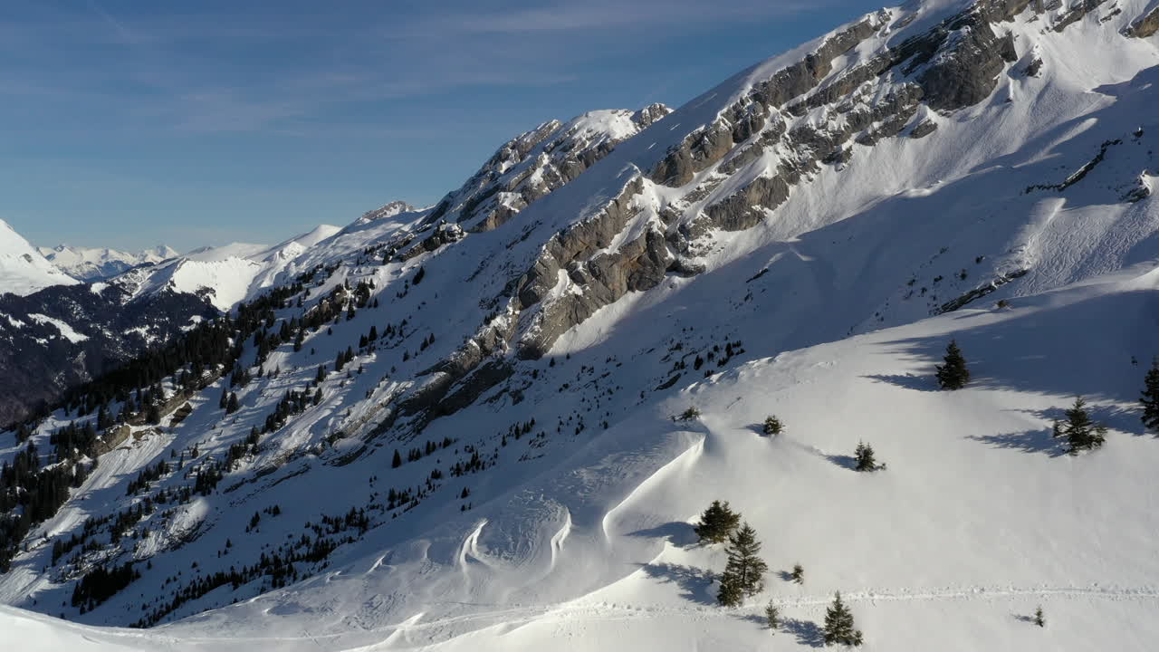 vista aérea, volando sobre la cresta de la montaña en los alpes franceses en invierno para revelar un valle de montaña con remontes