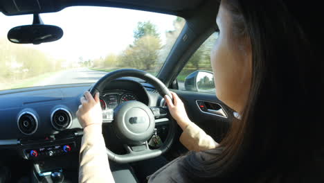 Young-woman-driving-in-a-car,-over-shoulder-view