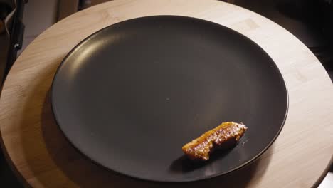 chef is placing fried chicken on a plate together with roasted vegetables