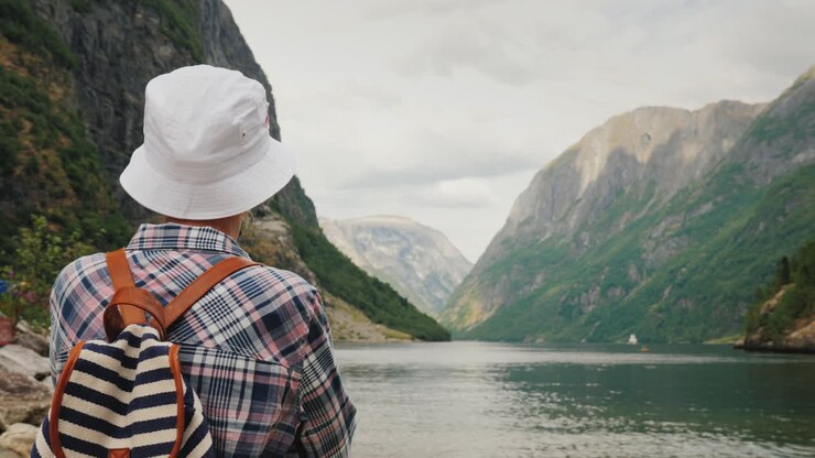 Ein Tourist mit Rucksack auf dem Rücken bewundert den malerischen Fjord in Norwegen Aktiver Lebensstil und Tourismus