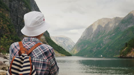 a tourist with a backpack on his back admires the picturesque fjord in norway active lifestyle and t