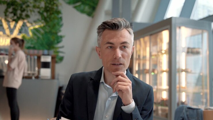 An Attractive Business Man Interviews Two People For A Job In A Coffee Shop