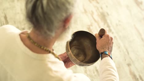 hombre mayor jugando bowl gong con un martillo