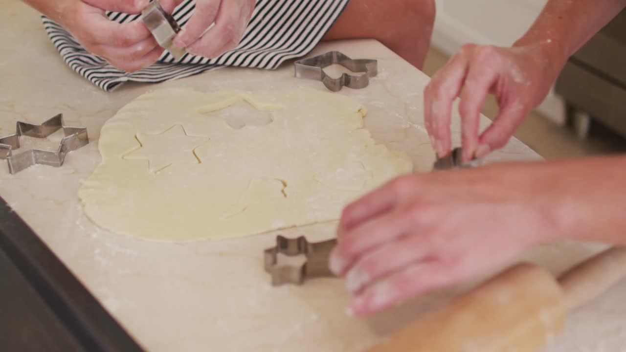 Mor og datter kutter deigen i stjerneformer med bakeformer på kjøkkenet.