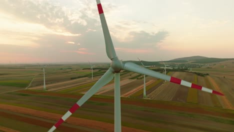 aerial view of the motion of a wind turbine against the backdrop of serene fields, showcasing renewable energy in action during a calm sunset