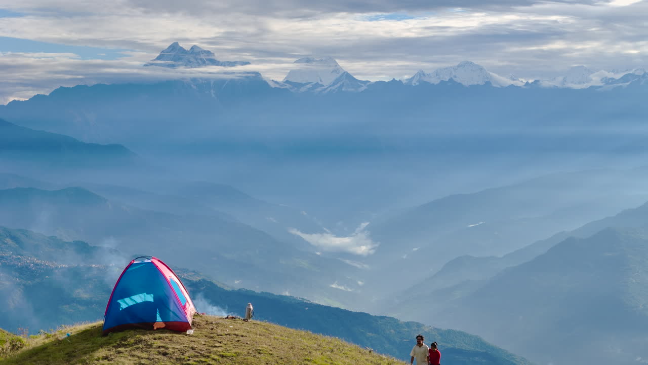 Drone shot captures couple enjoying a nature escape at Nepal Shailung, Dolakha, under a blue sky and clouds surrounded by bonfire warmth mountain ranges and the beauty of nature's horizon