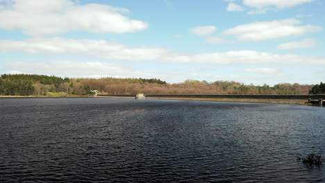 low aerial flyover of fewston reservoir from banks to water on sunny spring day