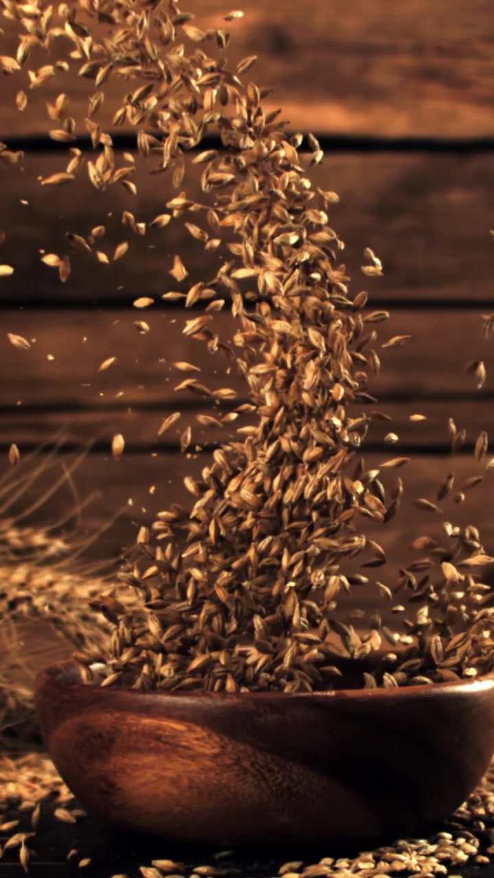 Chicchi di grano dorati che cadono in una ciotola di legno al rallentatore