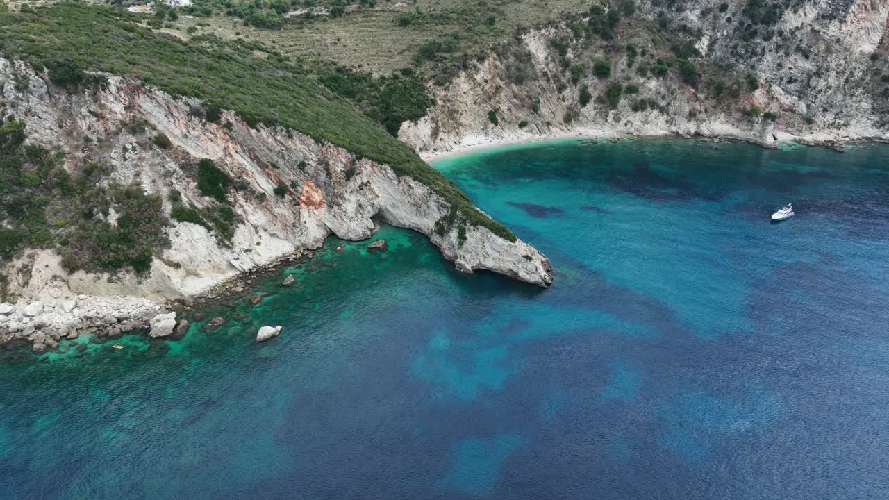 Aerial orbit showing Gjipe Beach’s turquoise waters, steep rocky cliffs, and a small anchored boat off the coast of southern Albania