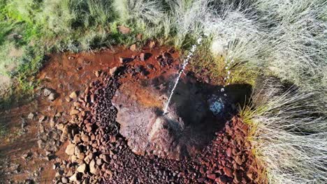 hot water geyser at fuendejalon spain with spurting water and iron deposits.